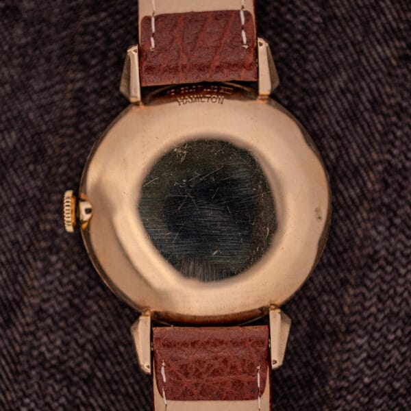 Hamilton Rodney Sector Dial Manual Wind watch, Cal. 748, with 10k gold filled case and brown leather strap, shown on a textured dark fabric background.