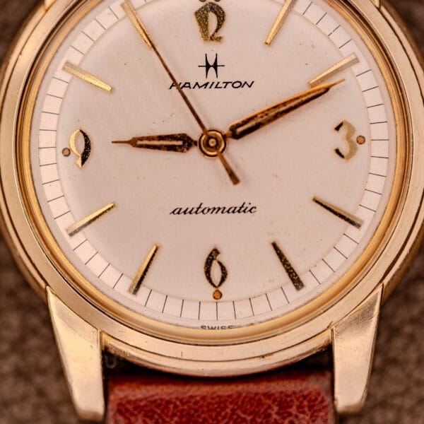 Close-up of a Hamilton Automatic Cal. 689 with a sunburst dial, 10k gold filled case, leather band, and stylized numerals.