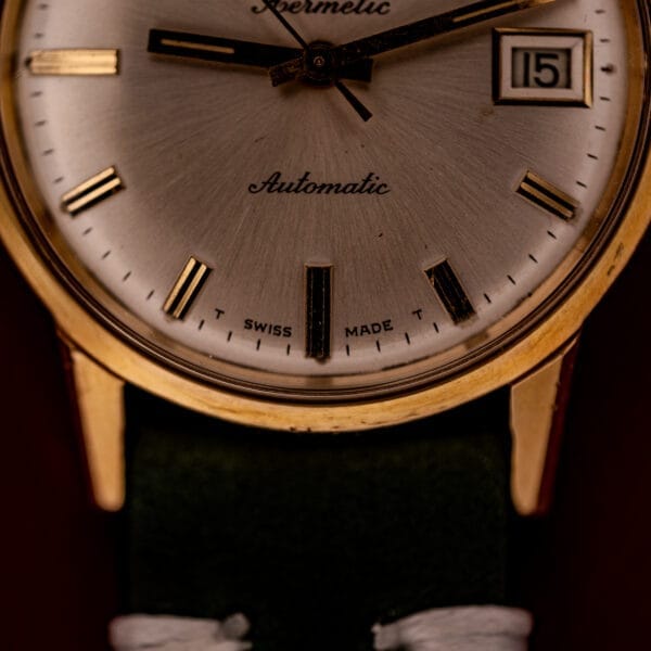 Close-up of the Zodiac Hermetic Date Ref. 723-917, featuring a vintage gold case, sunburst dial with date display, Automatic Cal. 70-72 movement, and "Swiss Made" on the face.