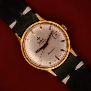 Zodiac Hermetic Date Ref. 723-917 face-on shot with silver sunburst dial, gold-tone baton markers, and green leather strap.