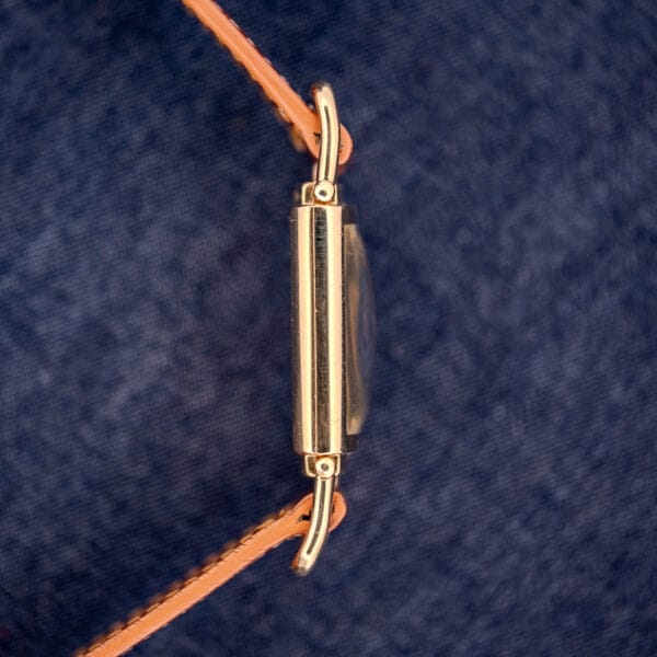 Side view of a Hamilton Willshire 14k Gold Filled Art Deco Case Cal. 980 wristwatch with a tan leather strap on blue denim, highlighting its elegant vintage design.