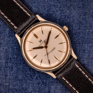 A 1962 Hamilton Thin-o-Matic Cal. 663 10K Gold Filled wristwatch with a black leather strap, displayed on denim fabric.