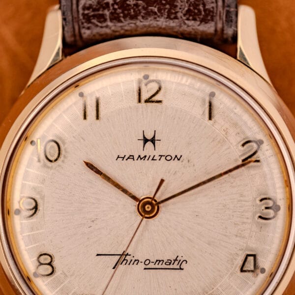Close-up of a 1966 Hamilton Thin-o-matic Cal. 668 wristwatch featuring a 10K Gold Filled case and a brown leather strap.