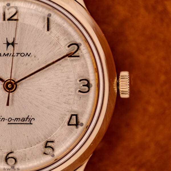 Close-up of a 1966 Hamilton Thin-o-matic Cal. 668 10K Gold Filled wristwatch, showing part of the dial, crown, and numbers 1 to 5 on its elegant case.