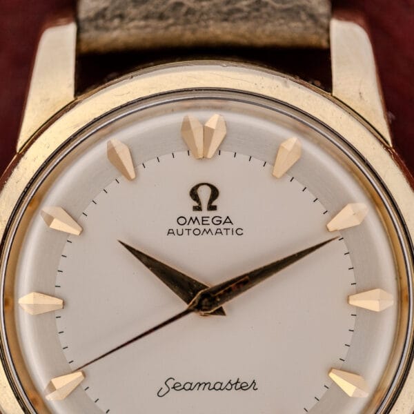Close-up of the Omega Automatic Seamaster Ref. 2846-2848 "Deluxe" with a gold capped case, gold markers, and a brown leather strap.