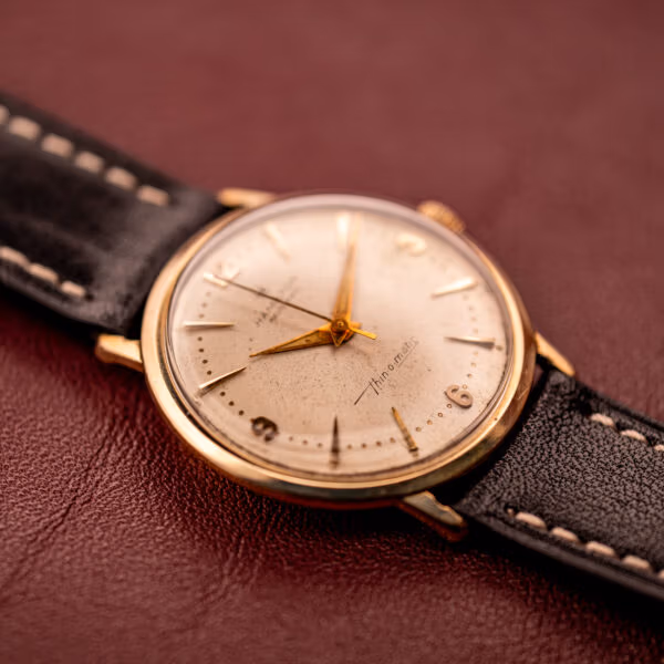 Hamilton Thin-O-Matic Masterpiece three-quarter angle showing polished gold-filled bezel, cream dial and black leather strap.