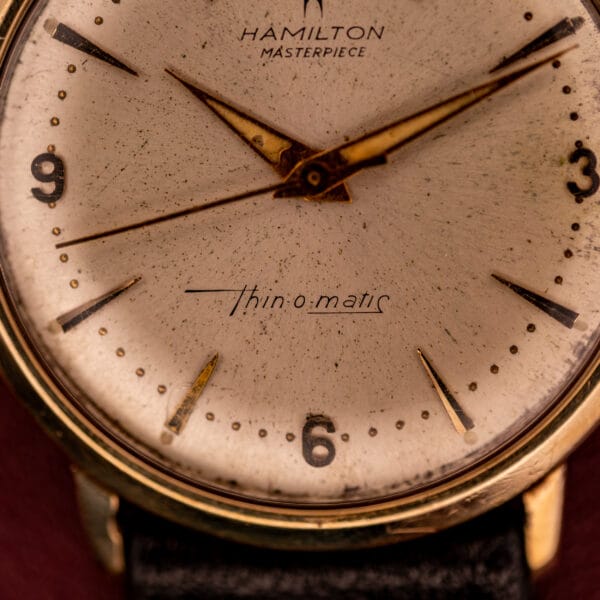 Close-up of a Hamilton Thin-O-Matic 10k Gold Filled Case Automatic wristwatch, showcasing its worn face and gold accents.