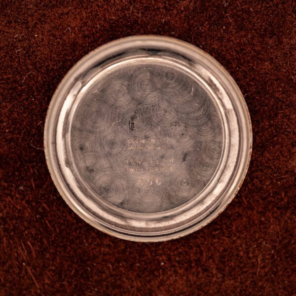 A round silver Zodiac Rotographic Ref. 656 pocket watch case back rests on a brown textured surface, displaying engraved maker's marks and Automatic Cal. 1381 details.
