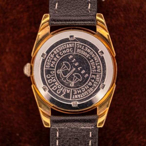 Back of Zodiac Rotographic Ref. 656 with engravings and black leather strap on brown background, highlighting its Tropic Dial and precise Automatic Cal. 1381 movement.