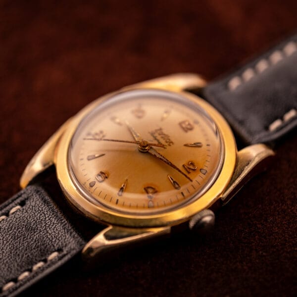 Close-up of a Zodiac Rotographic Ref. 656 Tropic Dial Automatic Cal. 1381 gold wristwatch with a black leather strap on a brown surface.