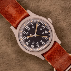 Top-down view of 1979 Hamilton GG-W-113 sterile black dial with aged tritium plots on brown leather strap.