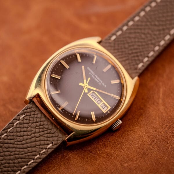 Three-quarter view of the Girard Perregaux Gyromatic showing the cushion case shape, signed crown at three, and warm brown dial in soft light.