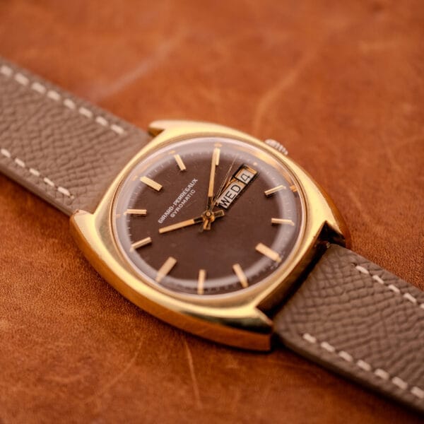 Three-quarter angled photograph of the Girard Perregaux Gyromatic 9276 HA showing the cushion case and brown dial on a grey calfskin strap.
