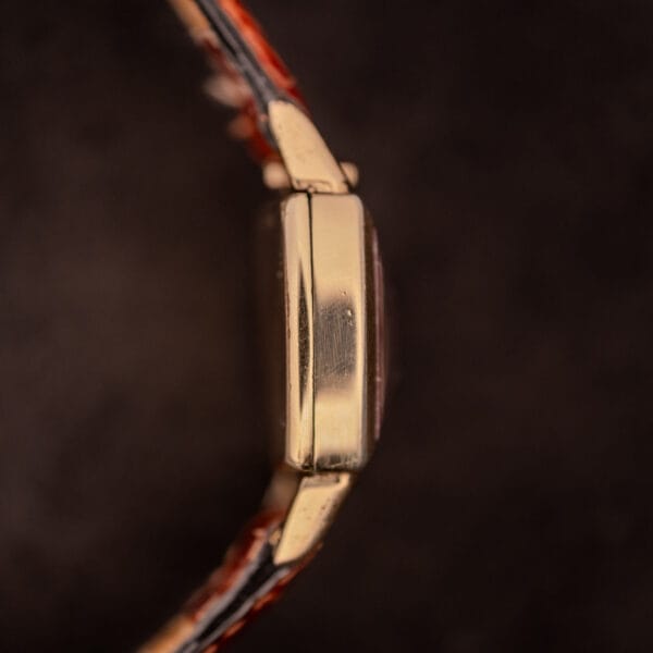 Side view of a Gruen "Top Crown" 10K Gold Filled 17 Jewels Ref. 400-298 c.1940s wristwatch with a brown leather strap, set against a dark background.