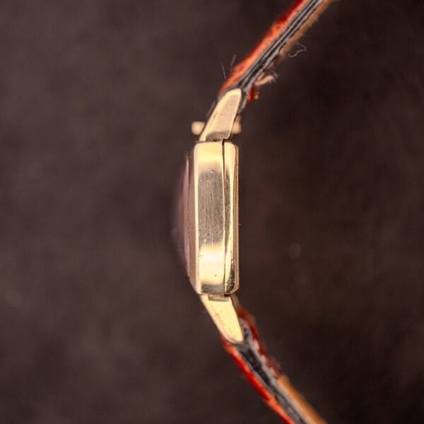 Side view of a Gruen "Top Crown" 10K Gold Filled 17 Jewels Ref. 400-298 c.1940s wristwatch with a worn brown leather strap, shown against a dark background.