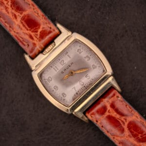 A Gruen "Top Crown" 10K Gold Filled 17 Jewels Ref. 400-298 c.1940s wristwatch with a square case and brown leather strap, displayed on a dark background.