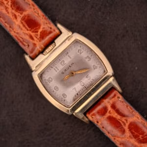 A Gruen "Top Crown" 10K Gold Filled 17 Jewels Ref. 400-298 c.1940s wristwatch with a square case and brown leather strap, displayed on a dark background.