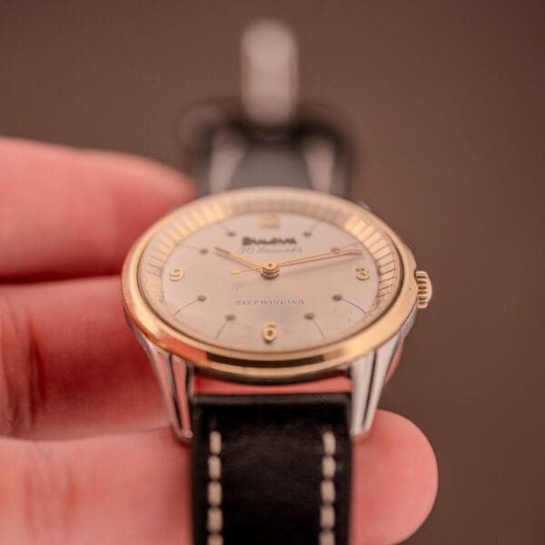 Close-up of a Bulova 30 Jewels Selfwinding Unishell Case wristwatch (Cal. 10BZAC, c.1961) with a 10K GF bezel and black leather strap, highlighting its classic craftsmanship and timeless style.