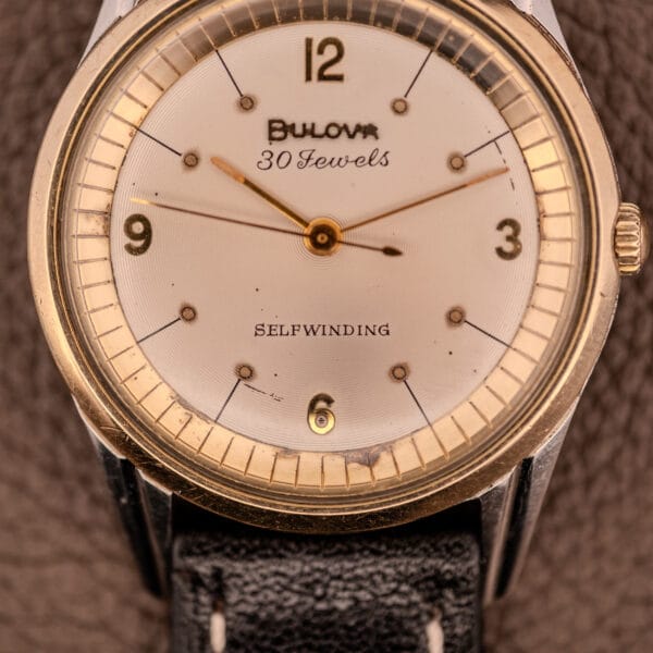 Close-up of a vintage Bulova 30 Jewels Selfwinding Unishell Case watch, Cal. 10BZAC c.1961, featuring a 10K GF bezel and leather strap.