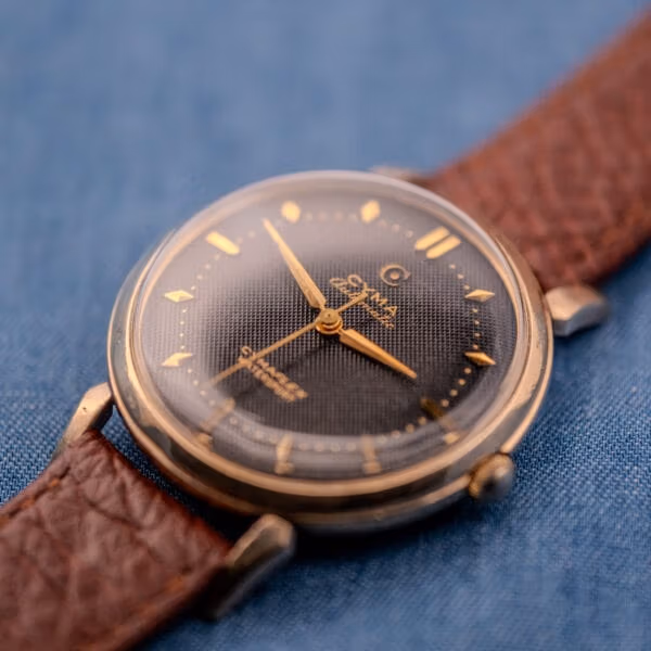 Angled view of the Cyma Cymaflex Watersport, honeycomb dial texture and gold accents catching warm light.