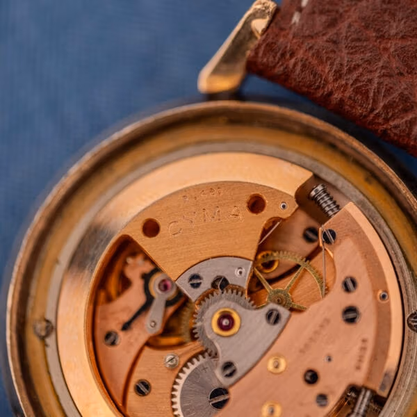 Macro of the Cyma R.420 movement showing CYMA engraving on the bumper rotor and visible balance wheel.