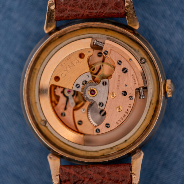 Close-up of a Cyma Cymaflex Watersport Automatic with Black Honeycomb Dial Cal. R.420, showing its exposed mechanical movement and gears, paired with a brown leather strap.