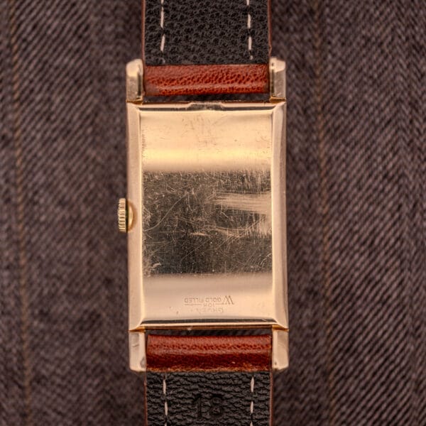 A Gruen Curvex Precision "Pyramid Crystal" 10K GF Ref. 370-601 gold rectangular wristwatch with a leather strap, shown from its scratched gold-filled back.