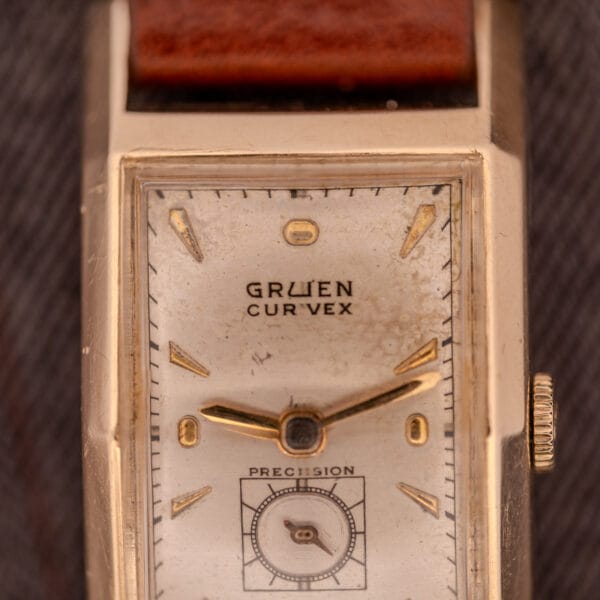 Close-up of a Gruen Curvex Precision "Pyramid Crystal" 10K GF Ref. 370-601 wristwatch featuring a rectangular case and brown leather strap.