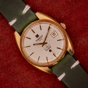Tissot Seastar Automatic Date Ref. 44660 Cal. 786-2 c.1970s with a gold case, white dial, green strap, and Automatic Date display on a red background.