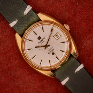 Tissot Seastar Automatic ref. 44660 front view, gold cushion case with silver sunburst dial and forest green leather strap on red velvet.