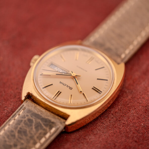 Bulova Automatic Ambassador Day-Date Ref. 7532-1 Cal. 11AOACB c.1970s with a worn leather strap, displayed on a textured red surface.