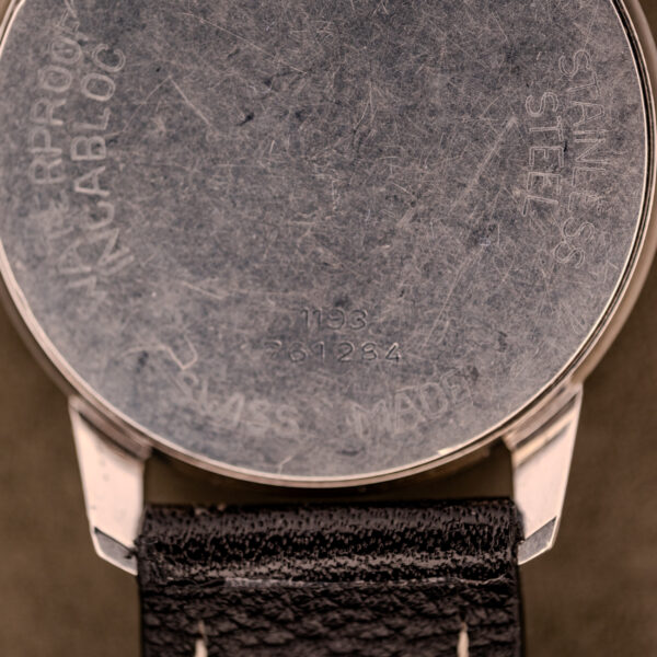 Close-up of the back of a scratched Baume & Mercier Compressor Manual Wind Ref. 1193 Cal. 391 c.1967 stainless steel wristwatch with a black leather strap.