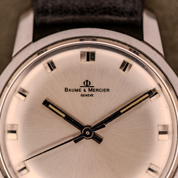Close-up of a Baume & Mercier Compressor Manual Wind Ref. 1193 Cal. 391 c.1967 wristwatch with a silver face and black leather strap.