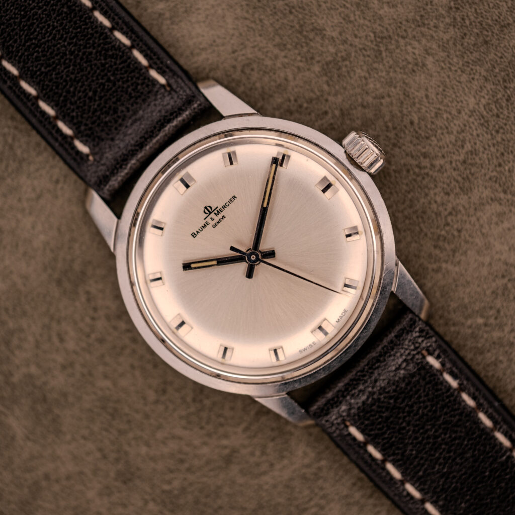 The Baume & Mercier Compressor Manual Wind Ref. 1193 Cal. 391 c.1967, with its classic design, rests on a textured brown surface, evoking the elegance of vintage timepieces from the renowned watchmaker.