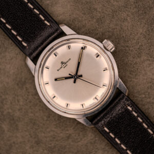 The Baume & Mercier Compressor Manual Wind Ref. 1193 Cal. 391 c.1967, with its classic design, rests on a textured brown surface, evoking the elegance of vintage timepieces from the renowned watchmaker.