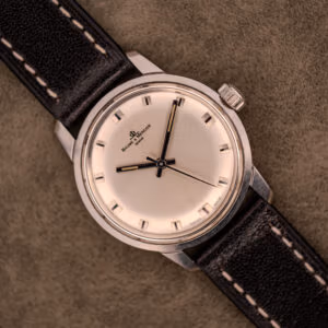 The Baume & Mercier Compressor Manual Wind Ref. 1193 Cal. 391 c.1967, with its classic design, rests on a textured brown surface, evoking the elegance of vintage timepieces from the renowned watchmaker.