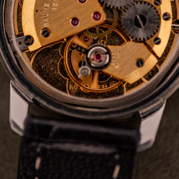 Close-up of the Baume & Mercier Compressor Manual Wind Ref. 1193 Cal. 391 (c.1967), showcasing its exposed mechanical movement and gears, with the black leather strap visible below.