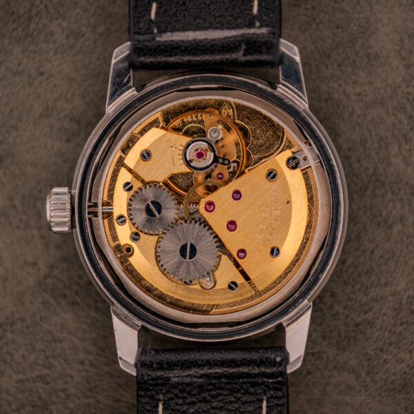 Close-up of a Baume & Mercier Compressor Manual Wind Ref. 1193 Cal. 391 c.1967, showcasing exposed gears, black strap, and metallic case with classic mechanical design.