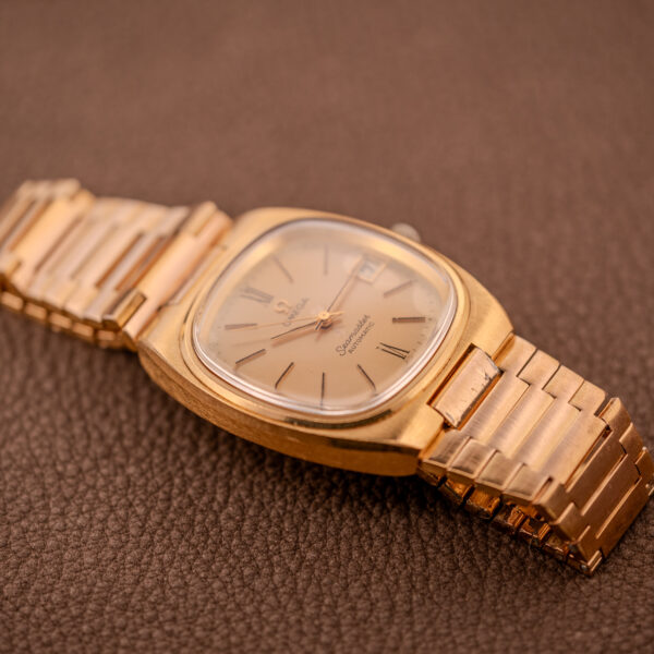 Omega Seamaster Automatic Date "TV Case" Ref. 166.0207 Cal. 1010 wristwatch with a square case and metal band, shown resting on a brown textured surface.