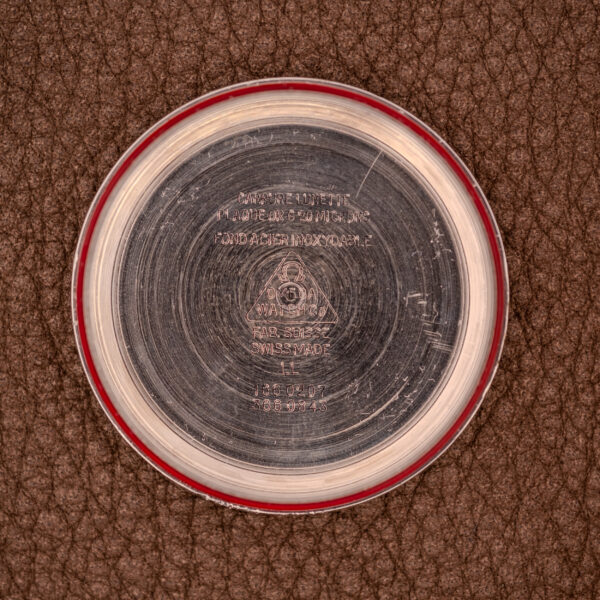 A round metal Omega Seamaster Automatic Date "TV Case" Ref. 166.0207 Cal. 1010 watch case back with engraved text rests on a brown textured leather surface.