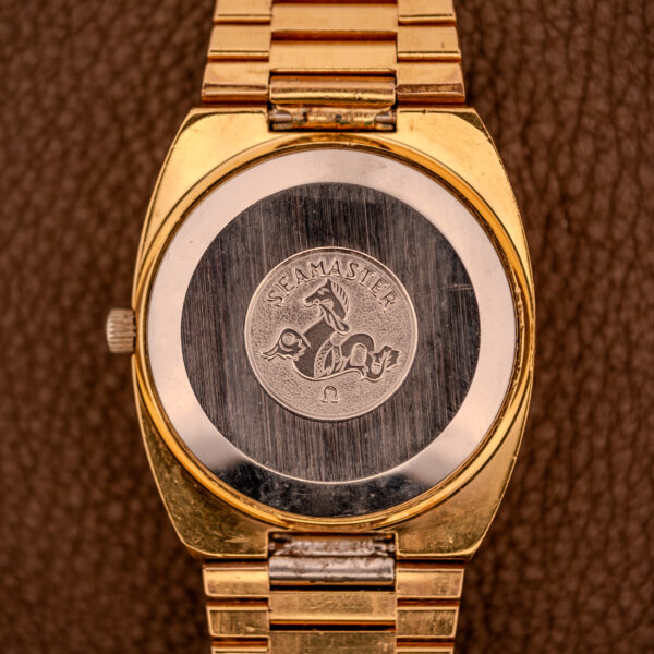 Omega Seamaster Automatic Date "TV Case" Ref. 166.0207 Cal. 1010 wristwatch with a seahorse engraved case back, shown on a brown textured surface.