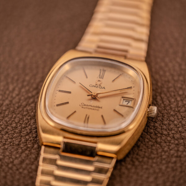 The Omega Seamaster Automatic Date "TV Case" Ref. 166.0207 Cal. 1010 rests elegantly on a textured brown surface.