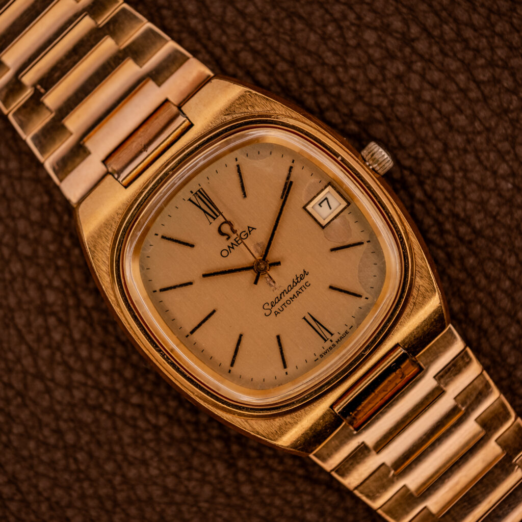 Omega Seamaster Automatic Date "TV Case" Ref. 166.0207 Cal. 1010 wristwatch with a rectangular case, shown on a textured brown surface.
