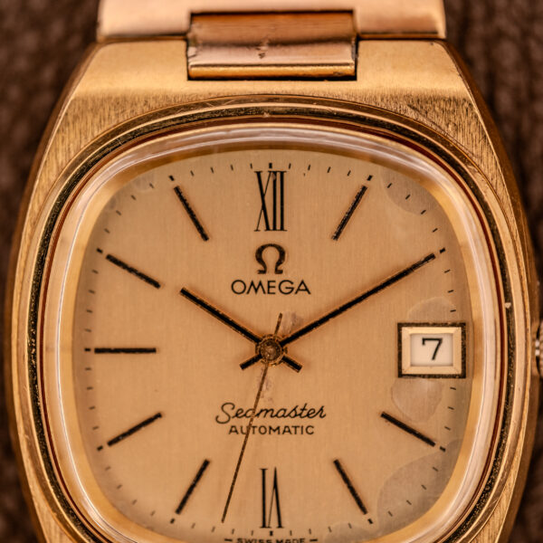 Close-up of an Omega Seamaster Automatic Date "TV Case" Ref. 166.0207 Cal. 1010, showcasing its vintage gold design and date set to the 7th.