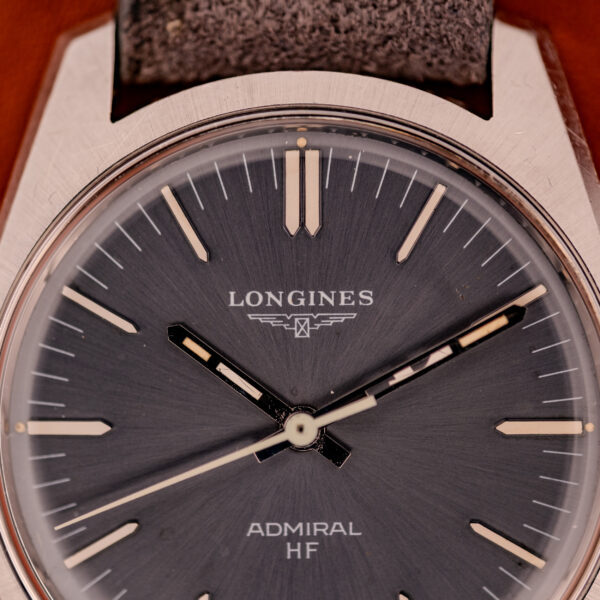 Close-up of a Longines Admiral HF Anthracite Sunburst Dial Ref. 2301 Cal. 6942 c.1972 displaying its anthracite sunburst dial with silver hour markers and hands against a dark background.