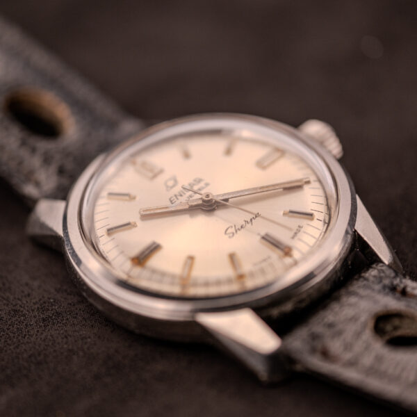 Close-up of an Enicar Sherpa Seapearl 600 Super Compressor Ref. 140/013 Cal. AR 1140 wristwatch with a worn black leather strap on a dark surface.
