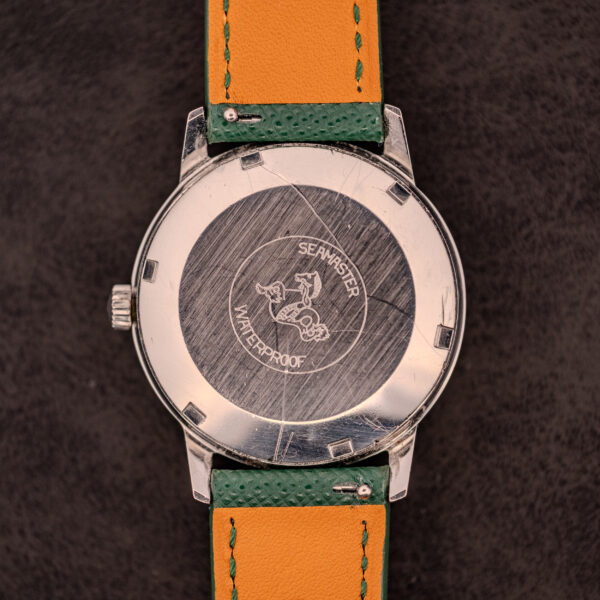 Back of an Omega Seamaster Automatic Date Ref. 166.037 (c.1968) with Seahorse logo and "Waterproof" engraving; green and orange strap. Features Caliber 565 automatic movement with date display.