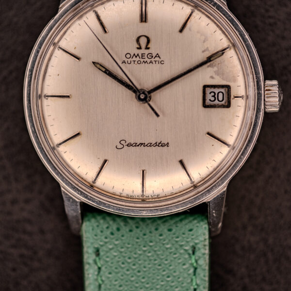 Close-up of an Omega Seamaster Automatic Date Ref. 166.037 (c.1968) featuring a Cal. 565 movement, green strap, and date window at three o’clock.