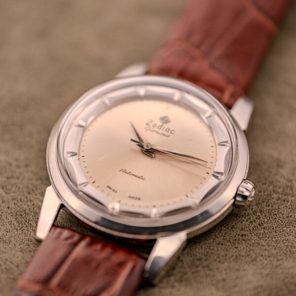Close-up of the Zodiac Glorious Automatic "Faceted Bezel" Ref. 696 Cal. 1624 wristwatch with a brown leather strap, shown on a textured surface.