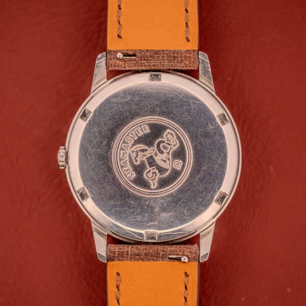 Omega Seamaster Automatic "Red Crosshair" Ref. 165.002 Cal. 552 with a silver case back featuring logo, on a tan leather strap against a red background.